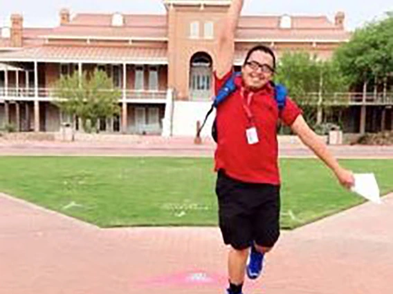 Student jumping up with a fist pump in front of old main