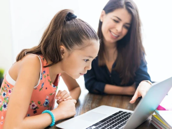 Young woman and child at table looking at laptop screen