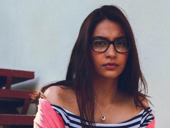 Portrait of a teenager wearing ripped jeans, a striped top, and pink cardigan