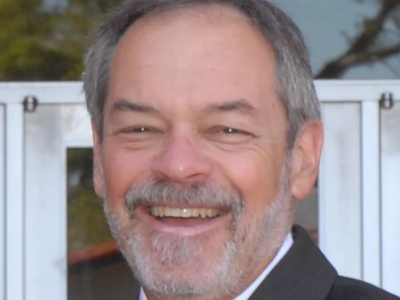 ron marx headshot, wearing a suit and tie, salt pepper hair, standing outside the college of education building