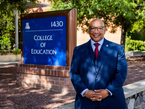 robert berry, dean of college of education, male black man standing under a shaded tree next to the college of education sign