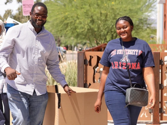 african american dad and daughter walking on campus under a sunny sky