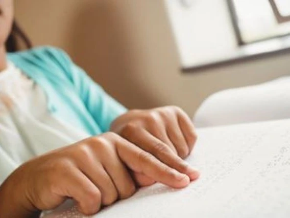 close up view of child hands reading braille