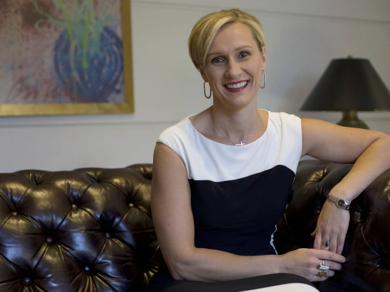kepic headshot, short blonde hair, black and white outfit, sitting on a couch