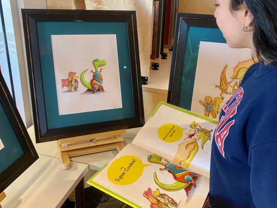 woman standing, looking at a book and illustration