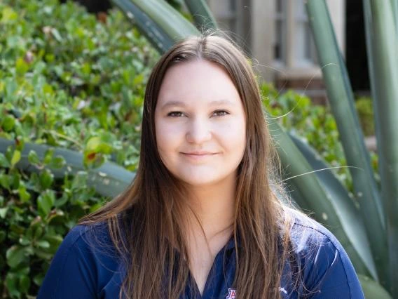 Bethany Kern, long light brown hair, wearing a blue shirt, greenery in the background