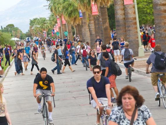 students walking and riding bikes on a campus path