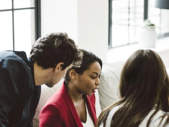 three adults conversing in office setting