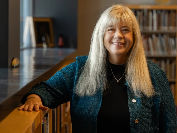 kathy short standing next to a bookcase in worlds of words