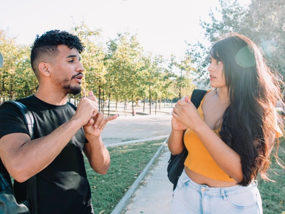 two young students signing to each other in an outdoor setting