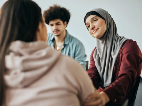 three students sitting at a table talking