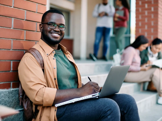 student sitting on steps with laptop on lap