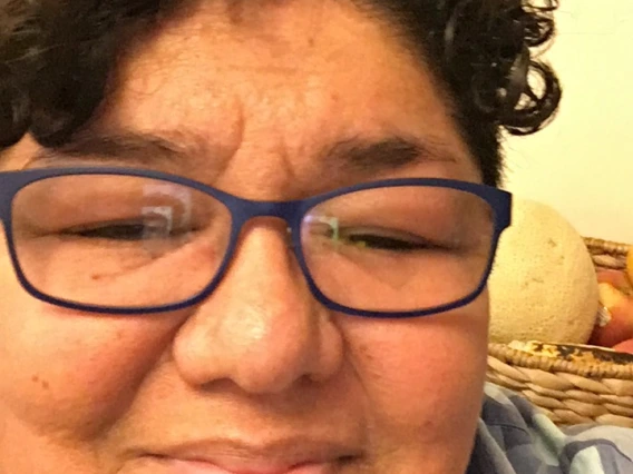 Cindy Cruz headshot, wearing eyeglasses, short black curly hair, plain blouse