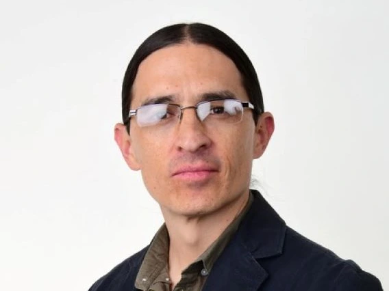 james mckenzie headshot, wearing eyeglasses, dark blazer, white background