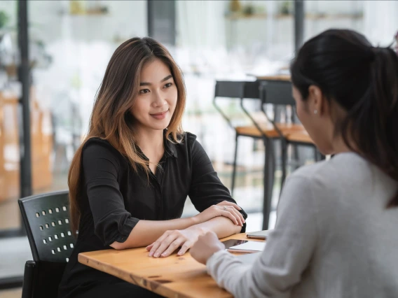 two women sitting at a table speaking to each other