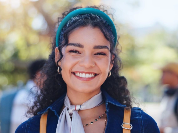 Woman, campus and student portrait with phd and smile at university ready for learning, education and class. Study, academy and happy post graduate candidate at college with backpack outdoor in park