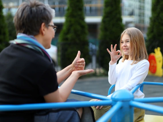 adult and child sitting in a playground signing to each other