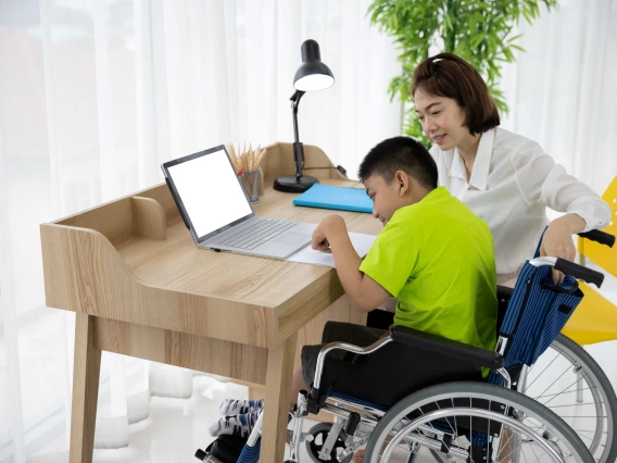 Asian boy with disability in wheelchair drawing picture with Laptop and mother at home. Supportive, Care, Coexistence and education