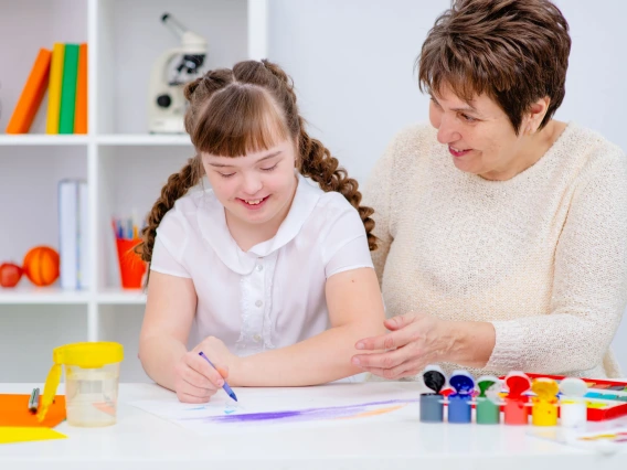 teacher and student working at a desk with paints