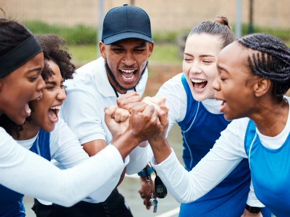 coach with a group of young female athletes in a huddle