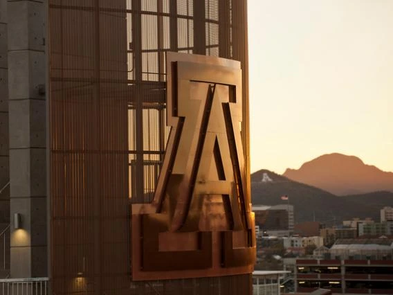 large copper colored u of a logo on the site of a building and sunset