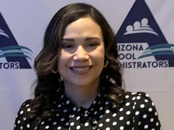 Flori Ceneno Huitt, wearing a polka dot black and white blouse, holding her award