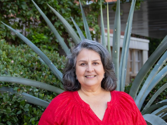 Cindy Trejo headshot, wearing a red blouse, standing in front of an agave plant