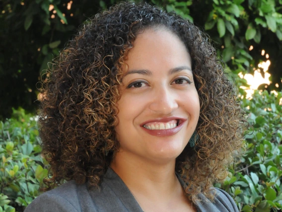 desiree vega headshot, wearing a floral blouse gray blazer, greenery as a backdrop