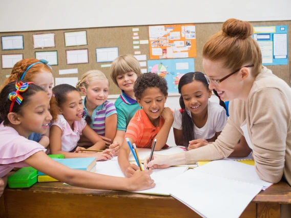 Teacher and pupils working at desk together