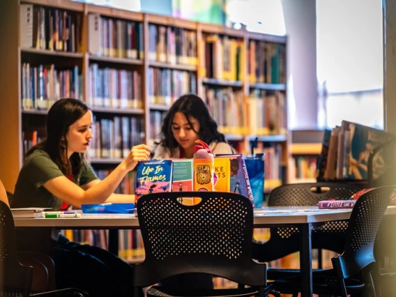 adult and child sitting at a table in a library