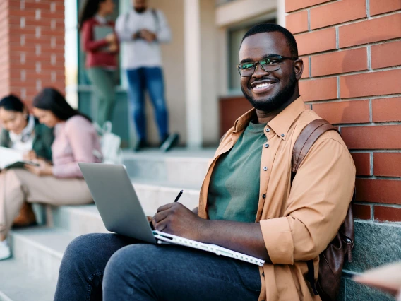 student sitting on steps with laptop on lap