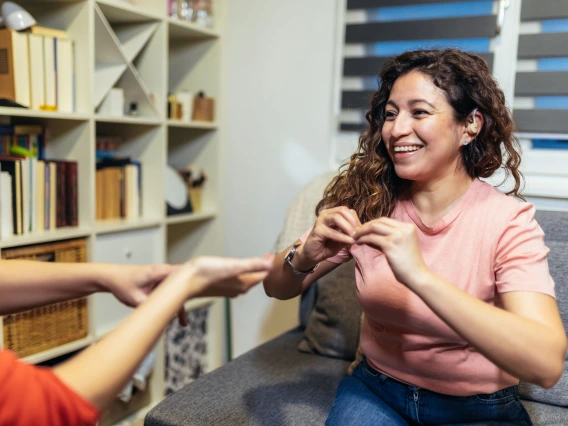 woman sitting across from another woman signing to each other