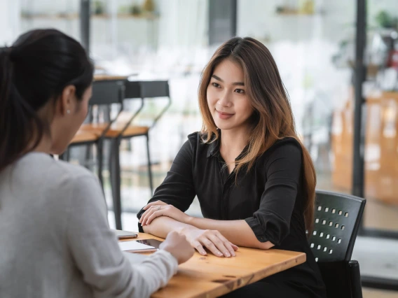 two women sitting at a table speaking to each other