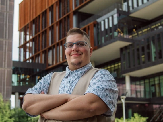 Octreyvian Killian standing outside, arms crossed, in front of a UA bldg