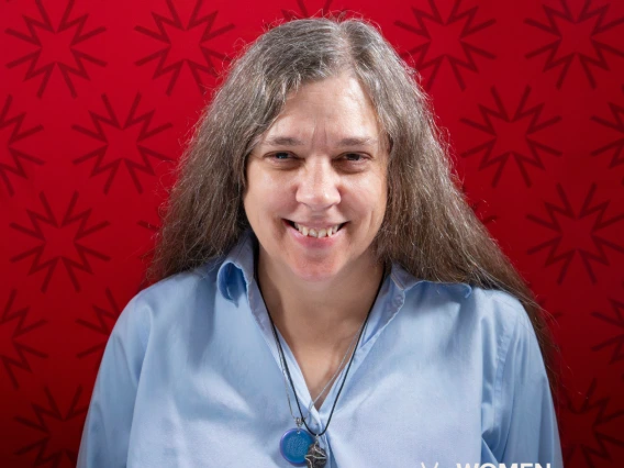 Dr. McKay-Cody, wearing a light blue blouse in front of a red background