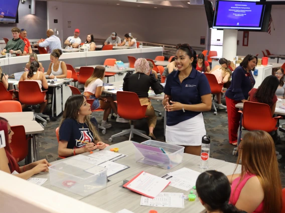 Group of students sitting at a table while an ambassadors collectively chats with them.