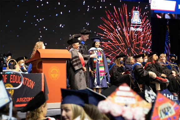 dean bruce johnson handing diploma to student on convocation stage