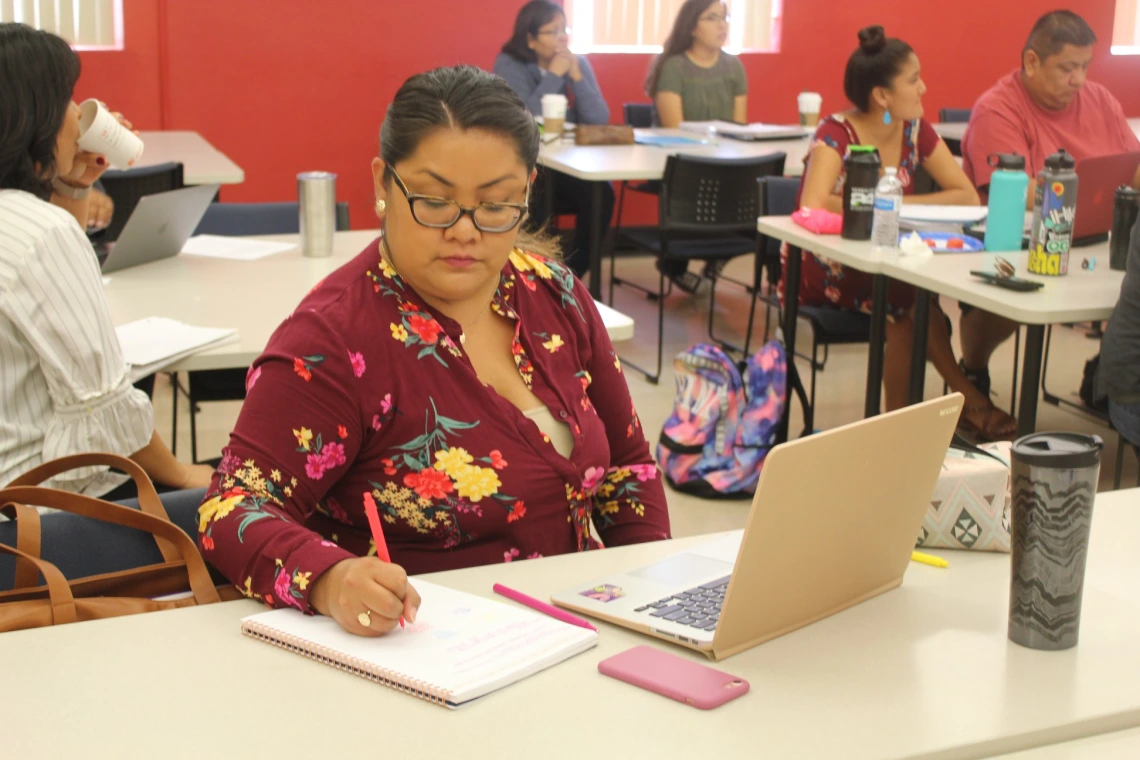 ITEP student taking notes during lesson with Dr. Norma Gonzalez