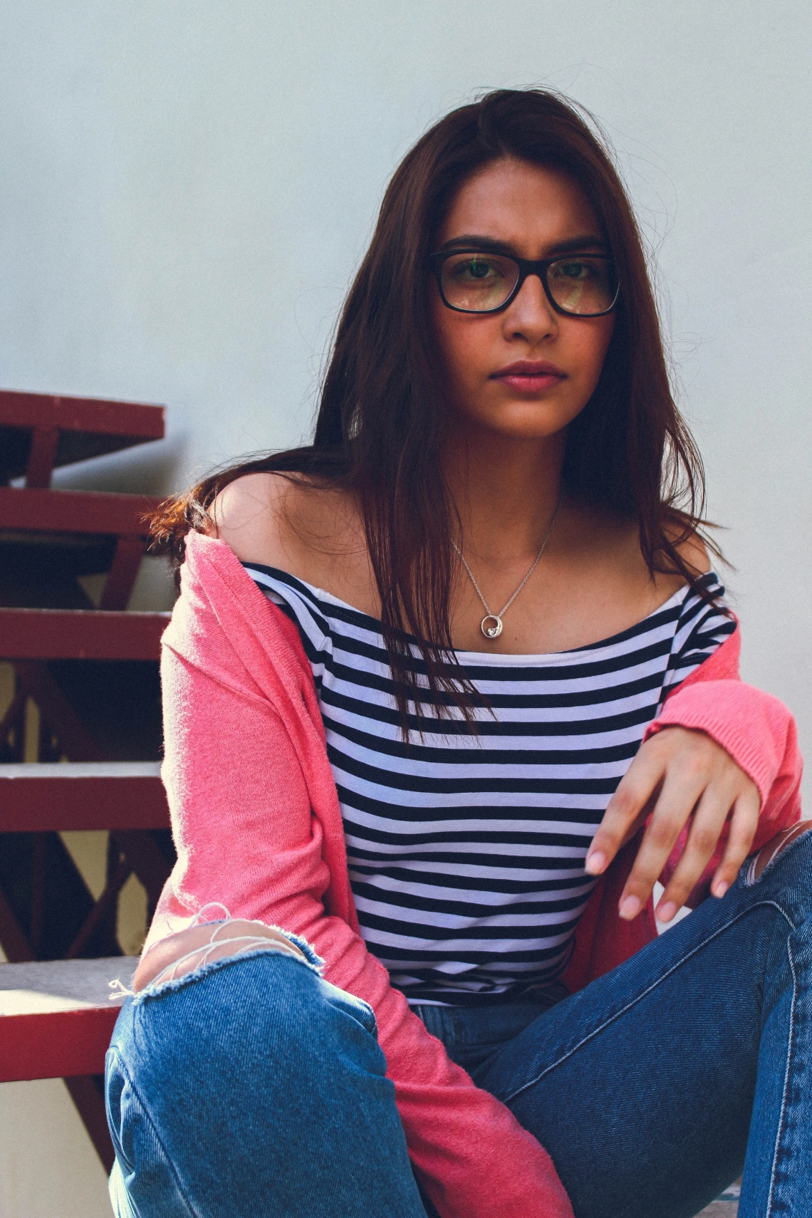 Portrait of a teenager wearing ripped jeans, a striped top, and pink cardigan