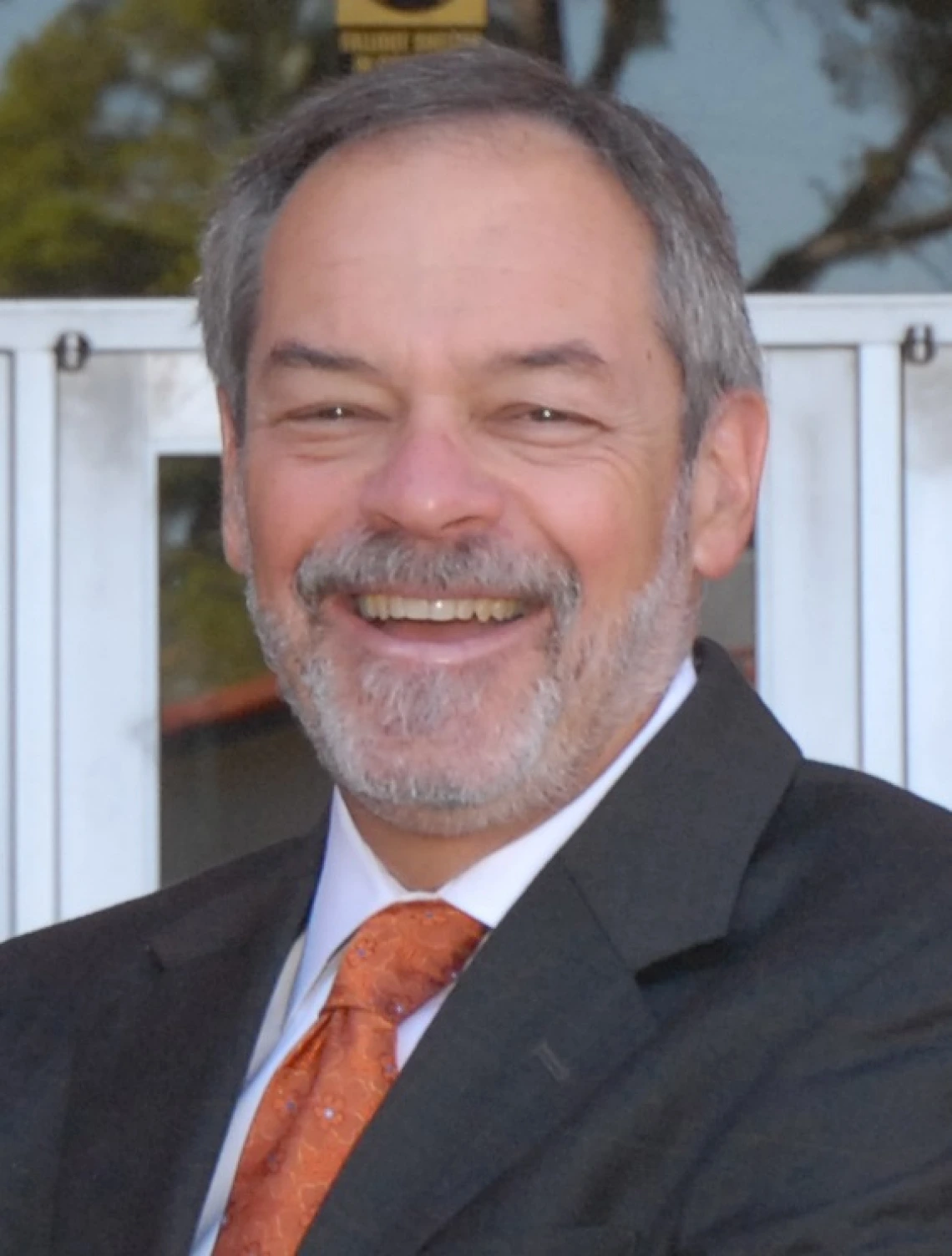 ron marx headshot, wearing a suit and tie, salt pepper hair, standing outside the college of education building