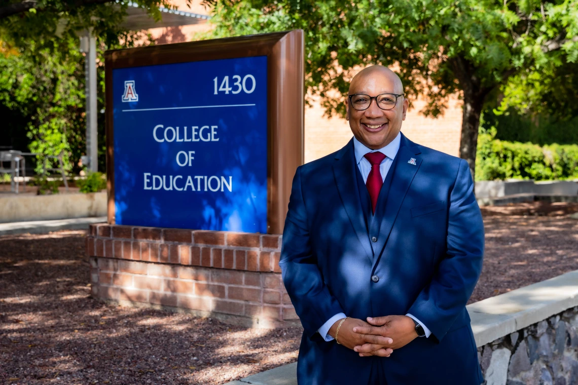 robert berry, dean of college of education, male black man standing under a shaded tree next to the college of education sign