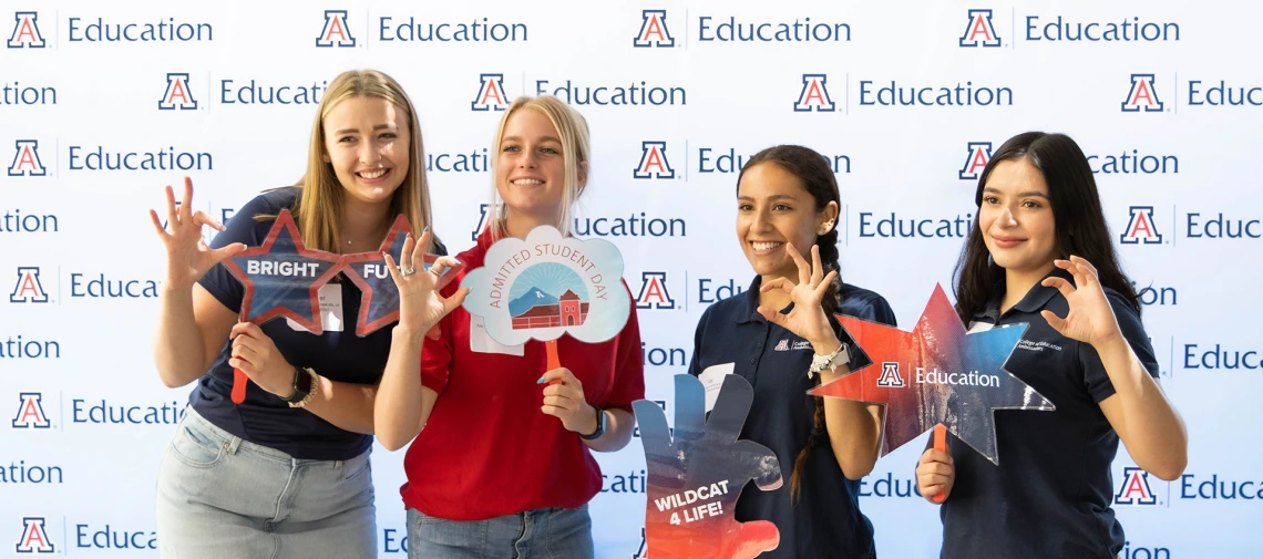 four young female students in front of the education banner