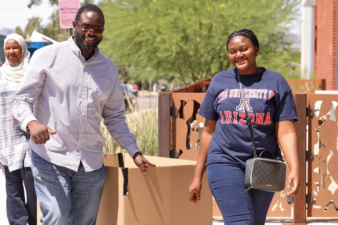 african american dad and daughter walking on campus under a sunny sky