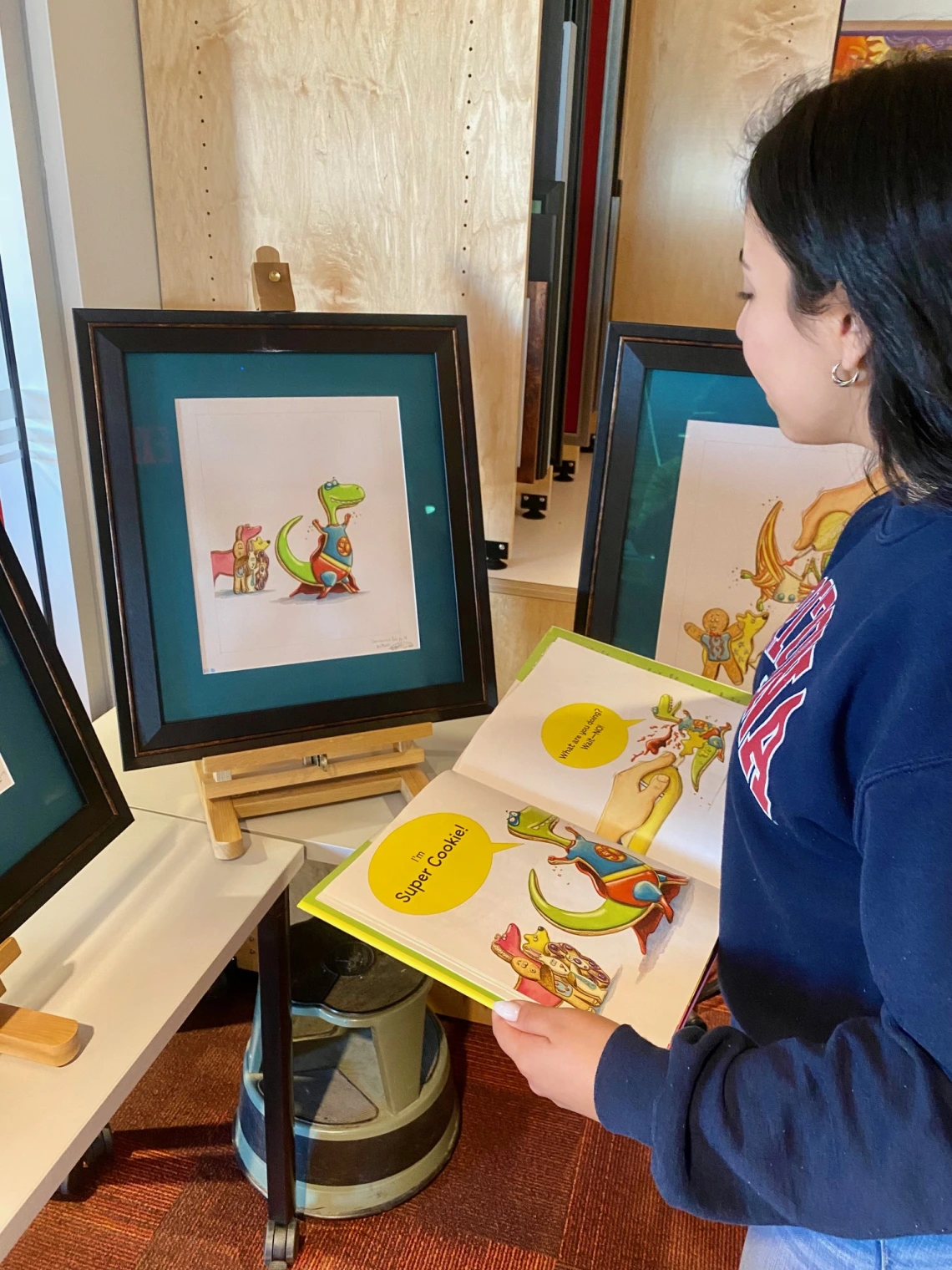 woman standing, looking at a book and illustration