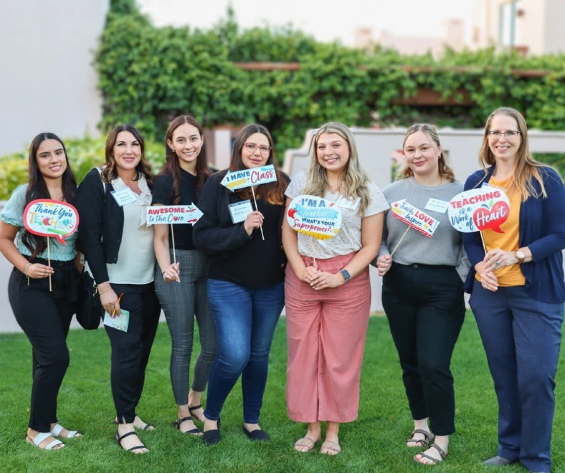 row of students holding teaching signs outdoor during az teaching fellow celebration