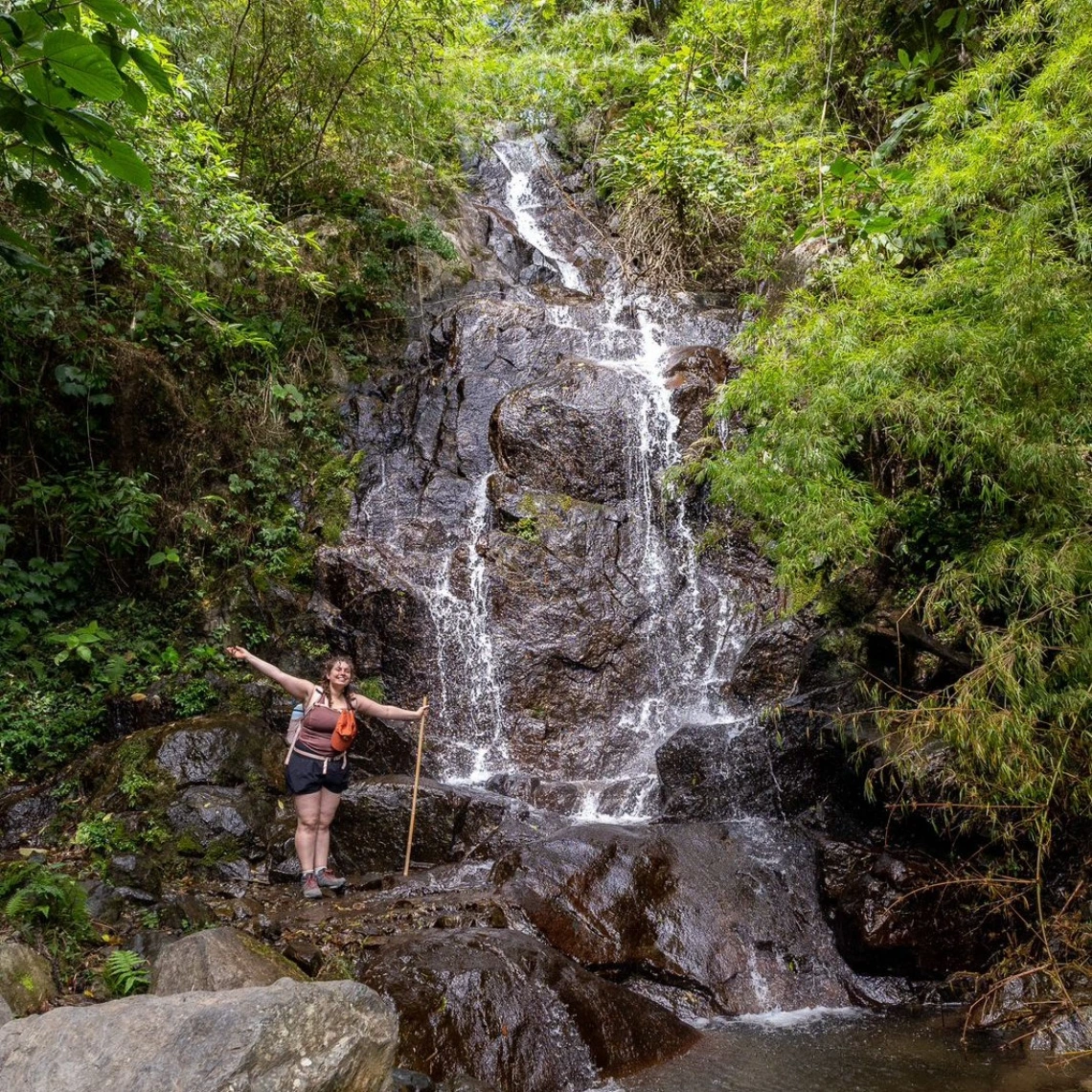 sarah rose standing in front of a waterfall in costa rica