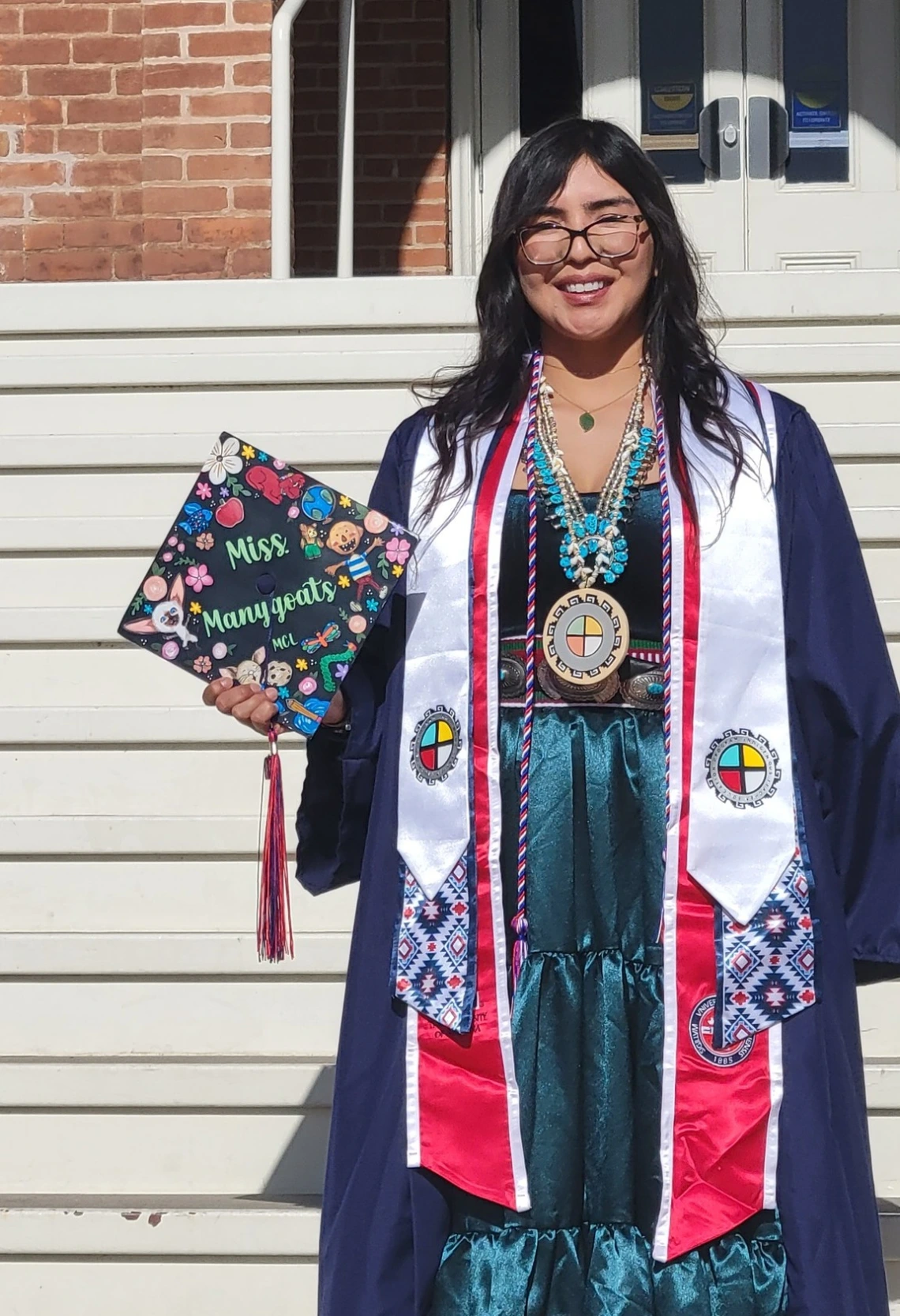 ITEP educator in graduation cap and gown on the steps of old main