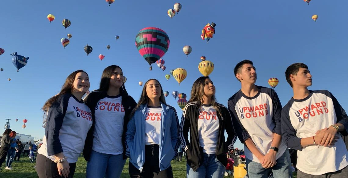 group photo of young adults hot air balloons in the distance