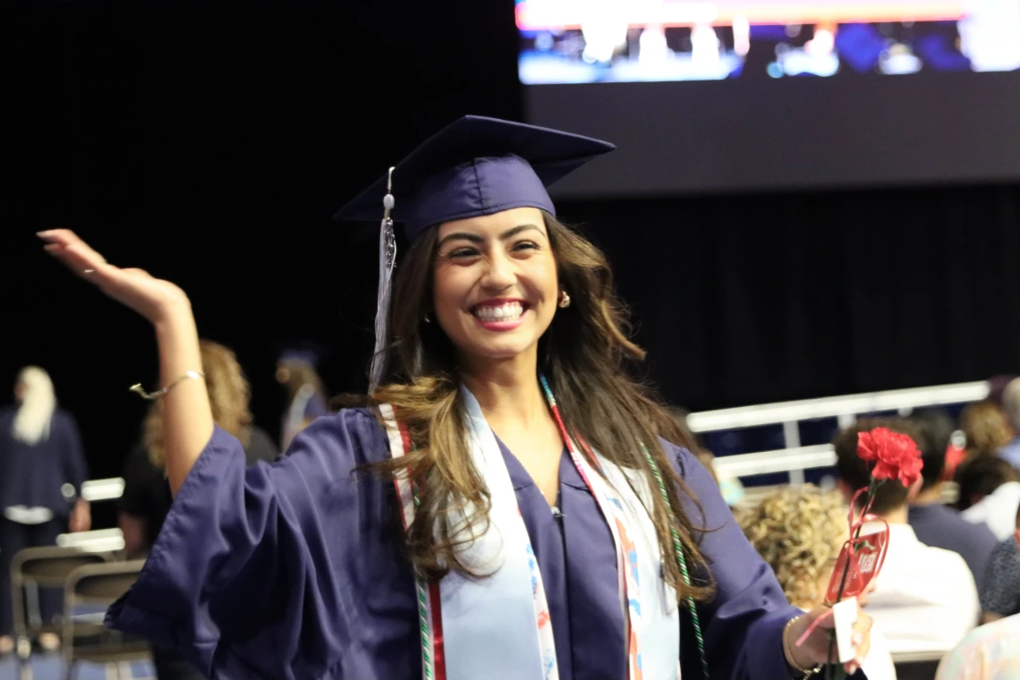 graduate in cap in gown waving