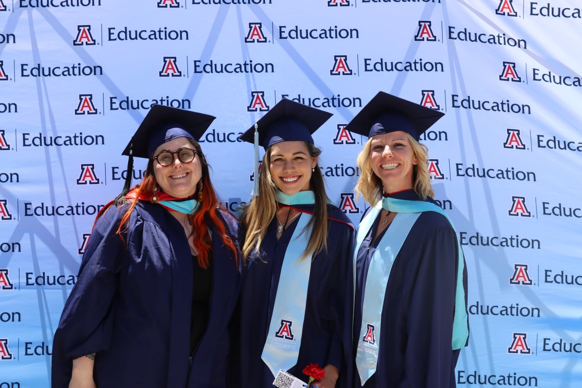 three young students in cap in gown posing for photo after convocation